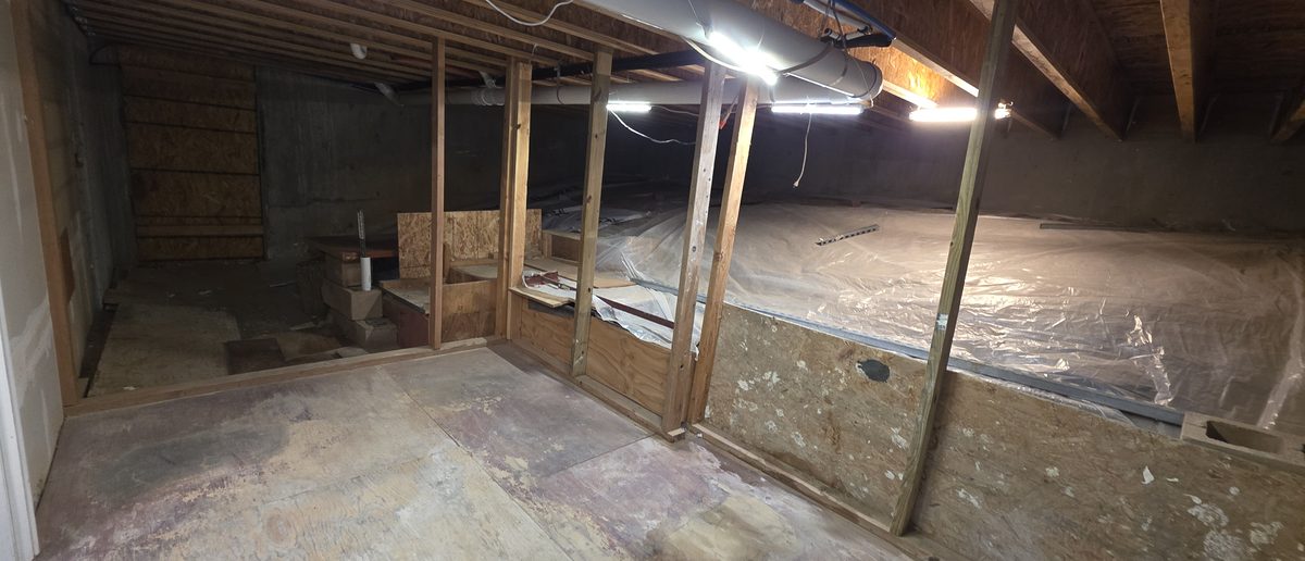 After: wide view of the same basement space cleared, open floor under the joists